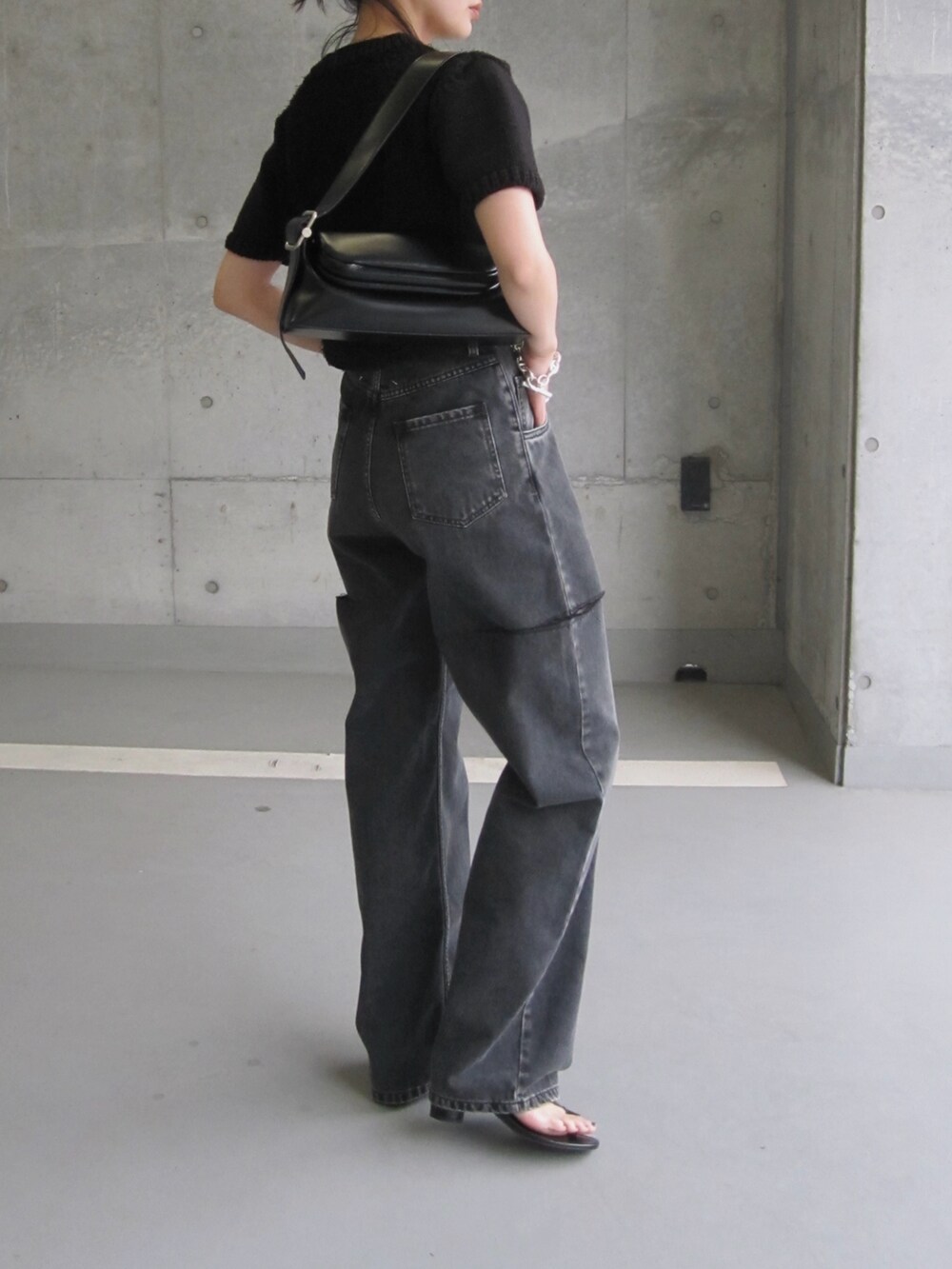 ブラック系のデニムパンツ、ブラック系のショルダーバッグ、ブラック系のニット/セーターを着用したレディースの春コーディネートの3枚目の写真