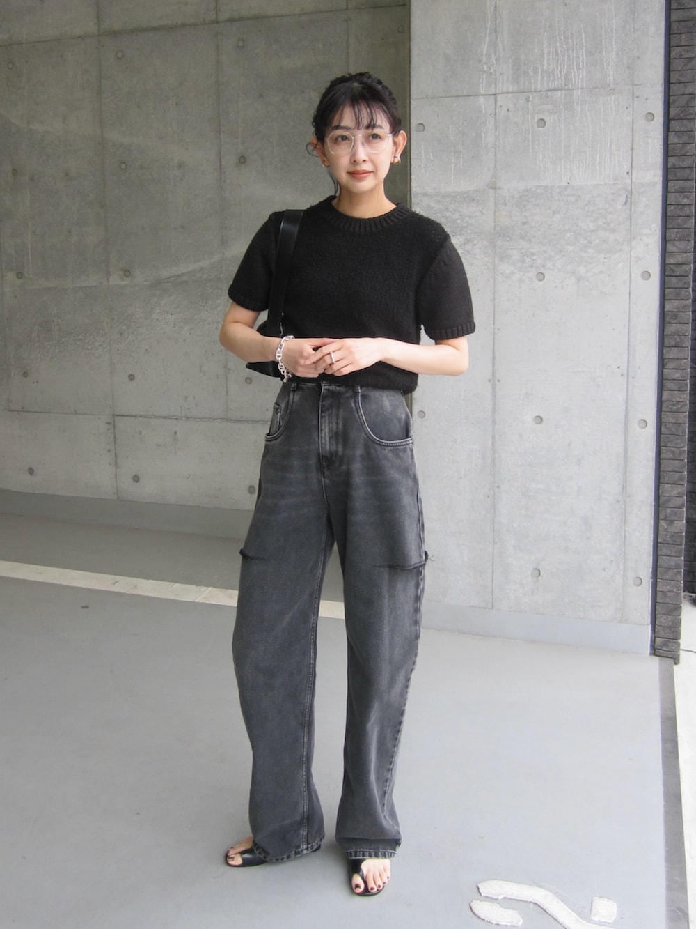 ブラック系のデニムパンツ、ブラック系のショルダーバッグ、ブラック系のニット/セーターを着用したレディースの春コーディネートの2枚目の写真