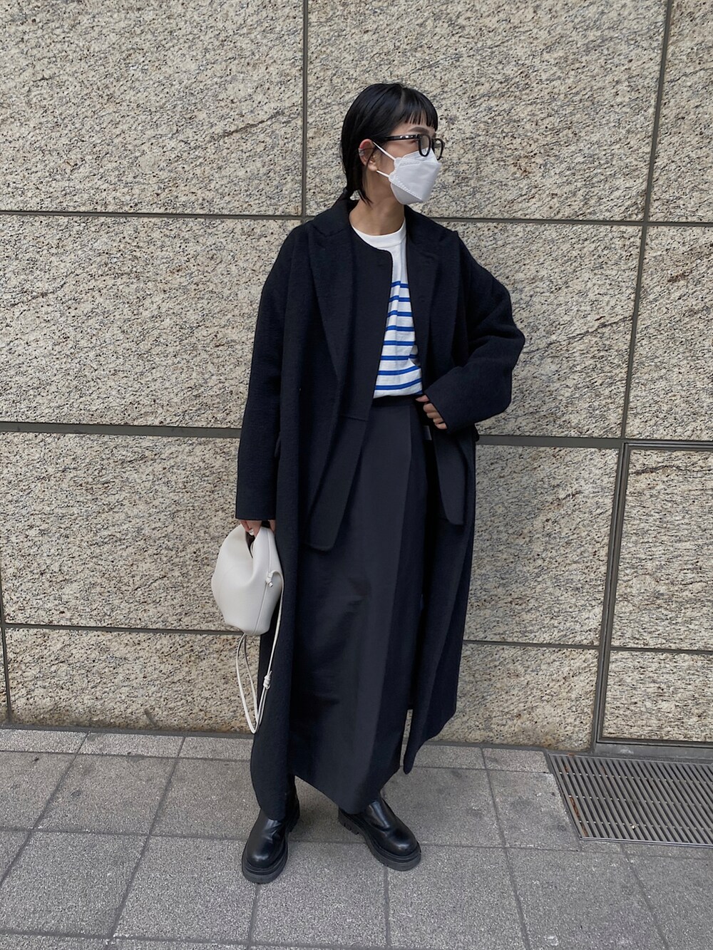 ブルー系のTシャツ/カットソー、ブラック系のチェスターコート、ブラック系のメガネを着用したレディースの冬コーディネートの4枚目の写真