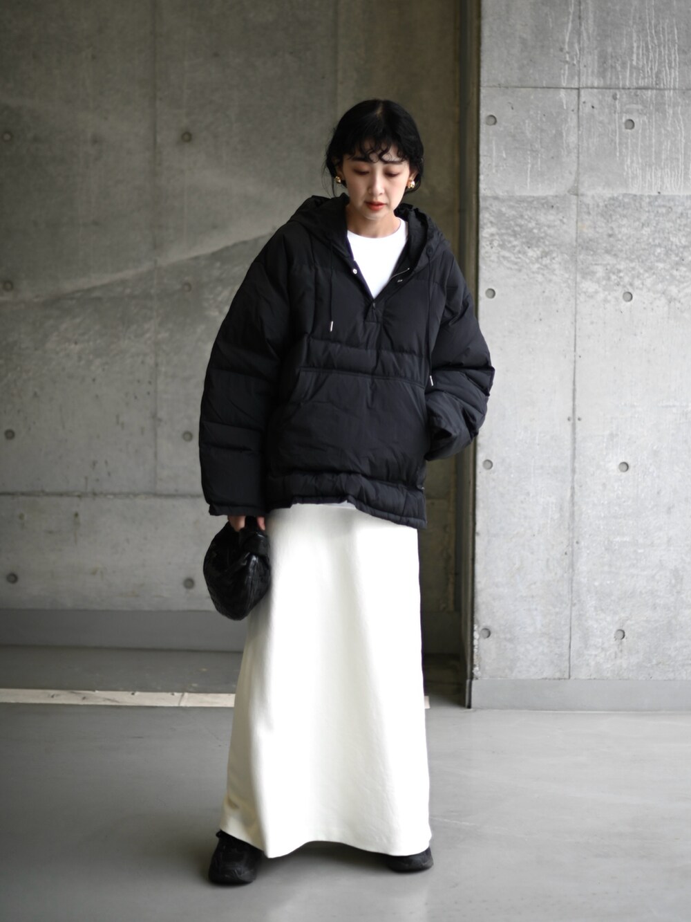 ブラック系のダウンジャケット/コート、ホワイト系のスカート、ブラック系のスニーカーを着用したレディースの冬コーディネートの5枚目の写真