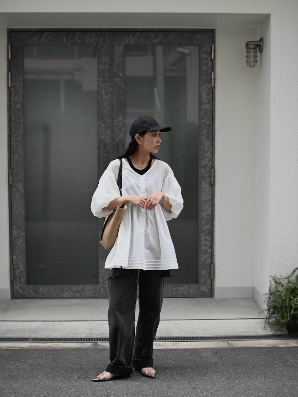 ホワイト系のチュニック、ブラック系のデニムパンツ、ベージュ系のトートバッグを着用したレディースの夏コーディネートの5枚目の写真