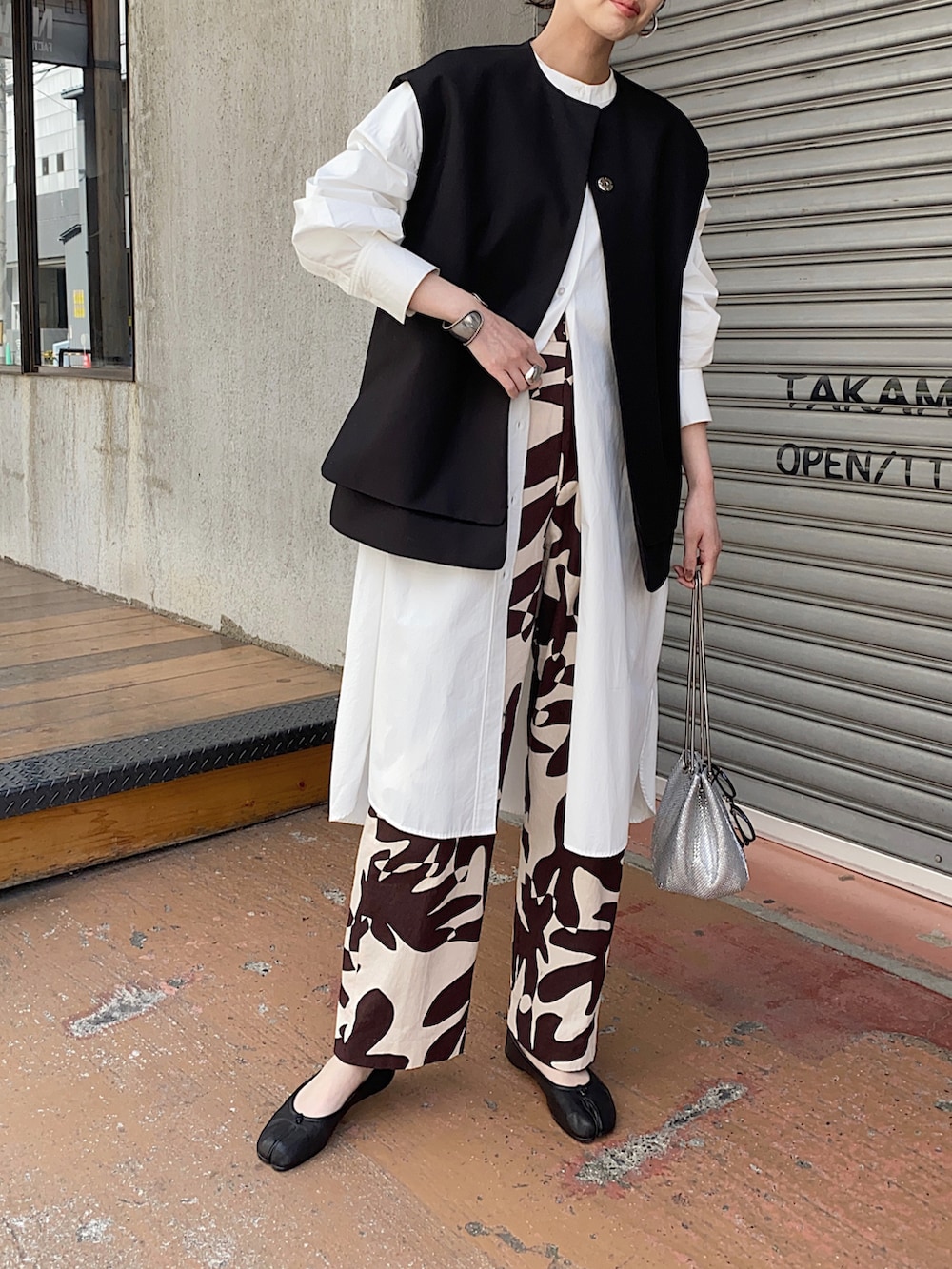 ブラック系のベスト、ホワイト系のシャツワンピース、ブラック系のバレエシューズを着用したレディースの春コーディネートの3枚目の写真