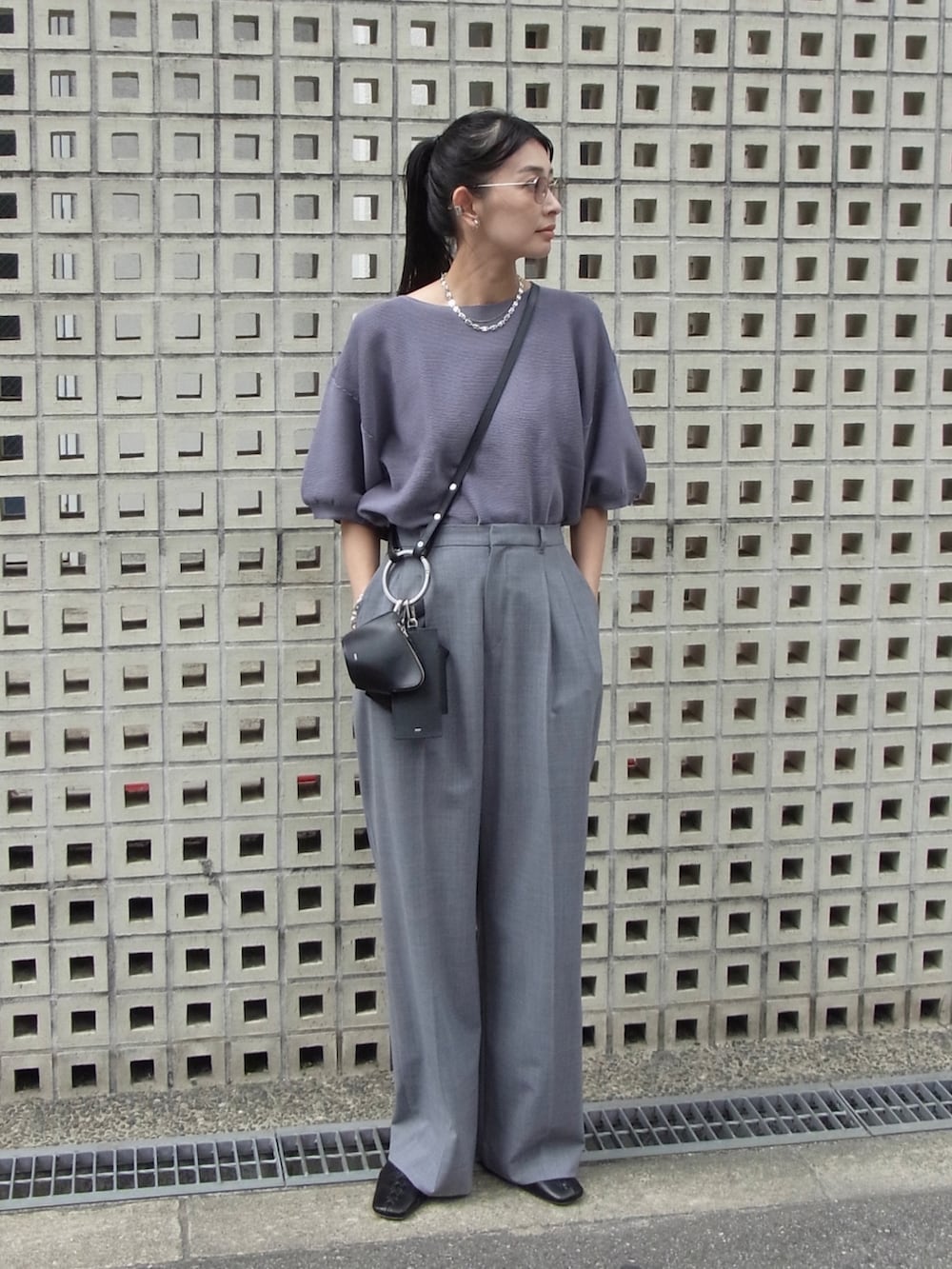 ブルー系のニット/セーター、グレー系のスラックス、ブラック系のショルダーバッグを着用したレディースの秋コーディネートの5枚目の写真