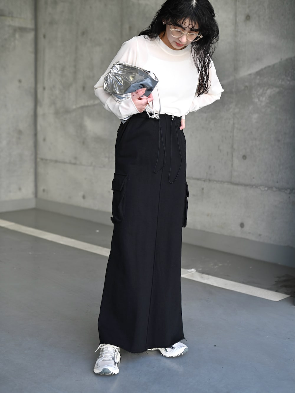 ホワイト系のTシャツ/カットソー、ブラック系のスカート、シルバー系のスニーカーを着用したレディースの夏コーディネートの3枚目の写真