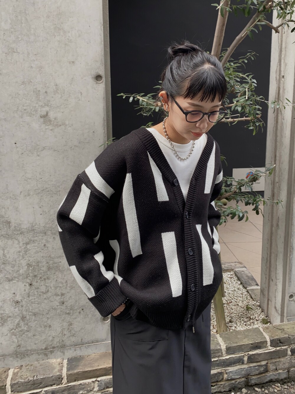 ブラック系のニット/セーター、ブラック系のブーツ、ホワイト系のTシャツ/カットソーを着用したレディースの秋コーディネートの2枚目の写真