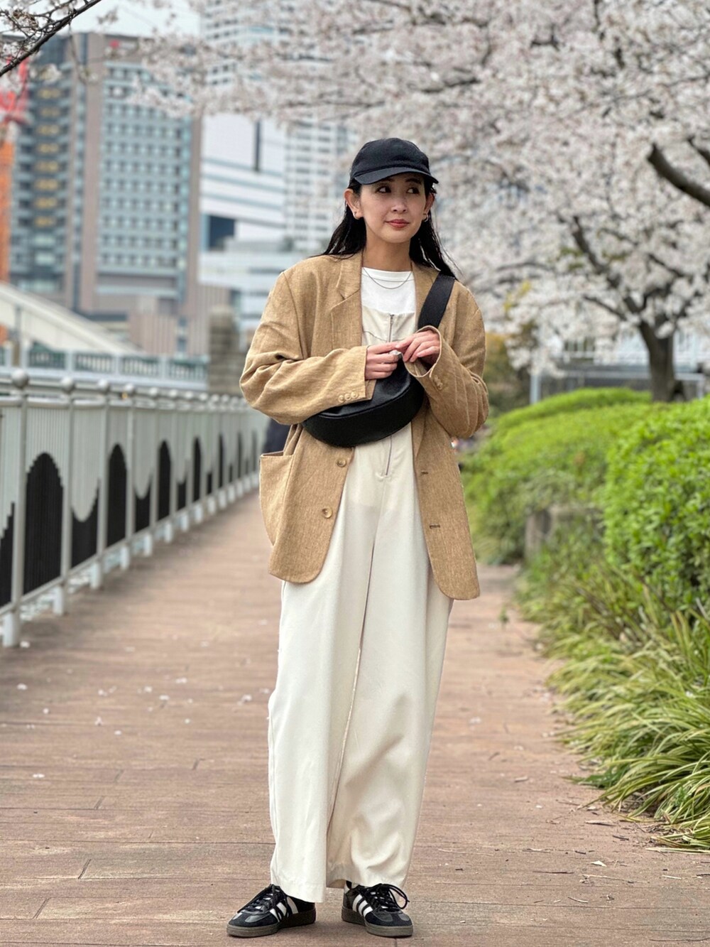 ブラック系のサロペット/オーバーオール、ブラック系のショルダーバッグ、ブラック系のスニーカーを着用したレディースの春コーディネートの2枚目の写真