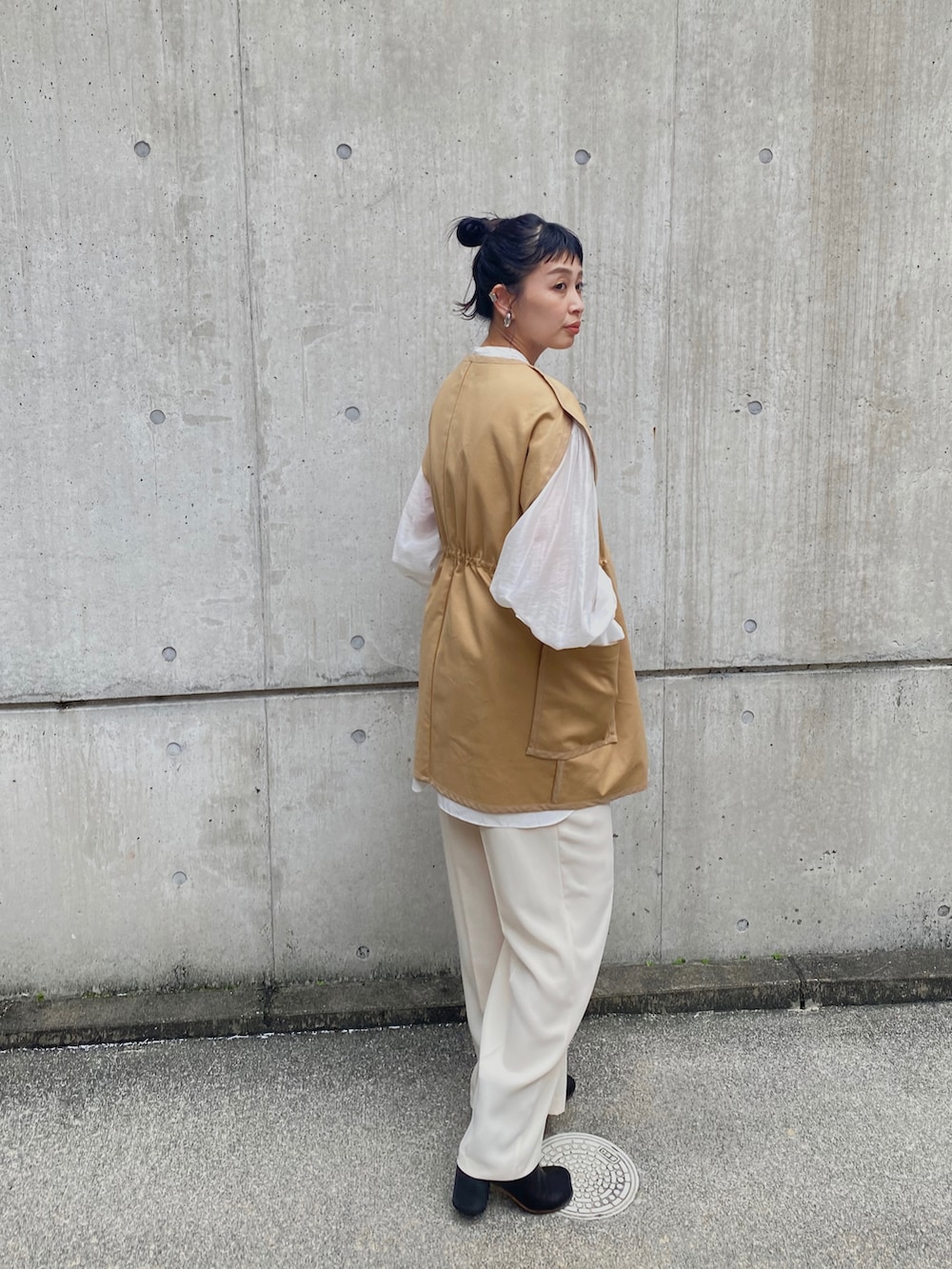 ホワイト系のシャツ/ブラウス、ブラック系のブーツ、ベージュ系のベストを着用したレディースの秋コーディネートの3枚目の写真