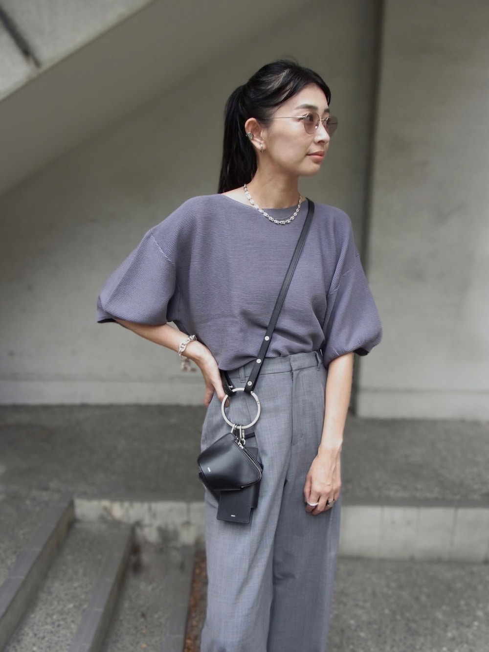 ブルー系のニット/セーター、グレー系のスラックス、ブラック系のショルダーバッグを着用したレディースの秋コーディネートの2枚目の写真