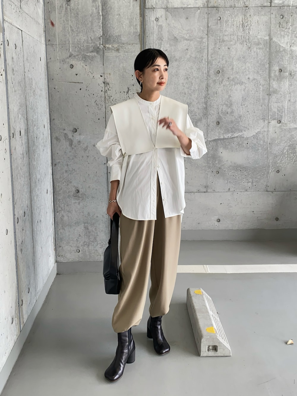 ホワイト系のベスト、ブラック系のブーツ、ブラック系のショルダーバッグを着用したレディースの春コーディネートの4枚目の写真