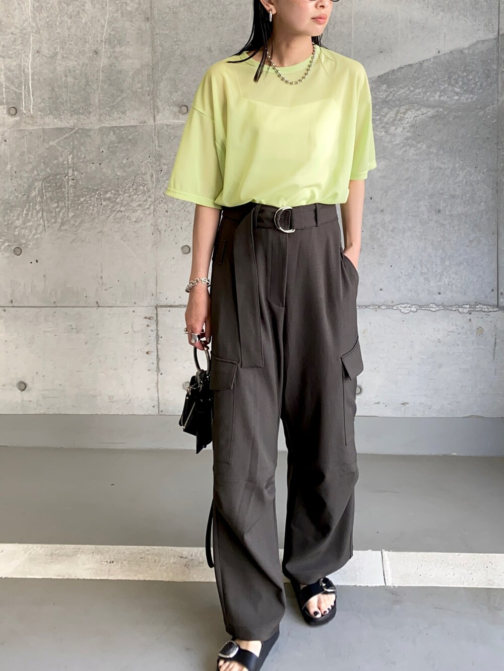 グリーン系のTシャツ/カットソー、ブラック系のスラックス、ブラック系のサンダルを着用したレディースの夏コーディネートの2枚目の写真