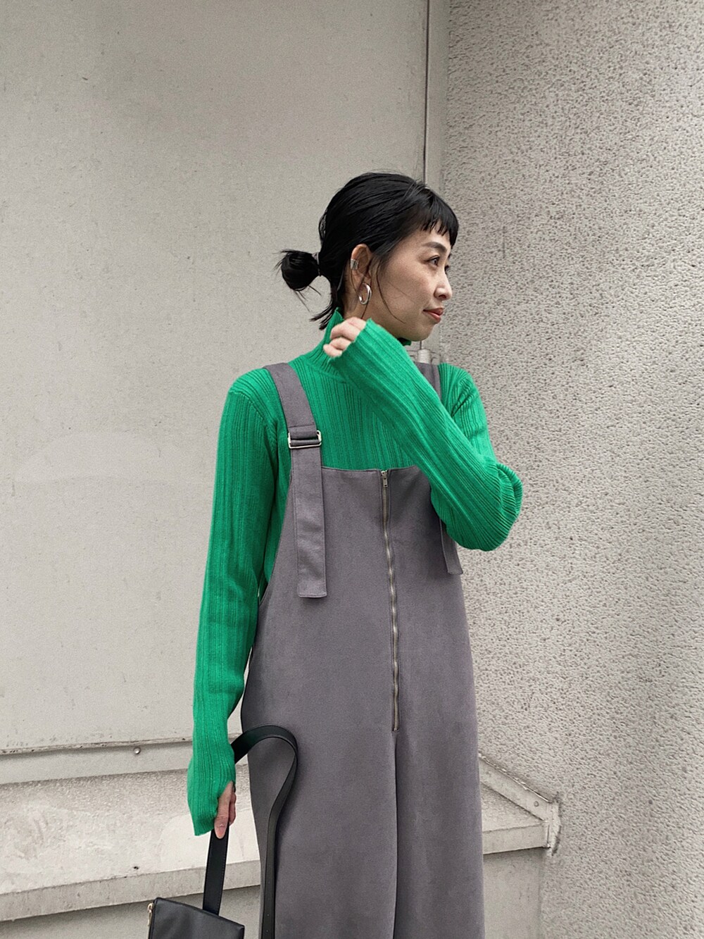 グレー系のサロペット/オーバーオール、グリーン系のニット/セーター、ブラック系のショルダーバッグを着用したレディースの冬コーディネートの2枚目の写真