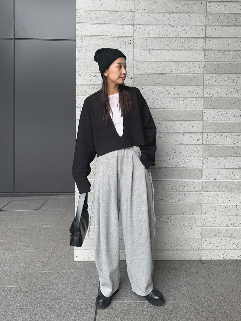 ブラック系のニット/セーター、グレー系のスウェットパンツ、ブラック系のショルダーバッグを着用したレディースの秋コーディネートの5枚目の写真