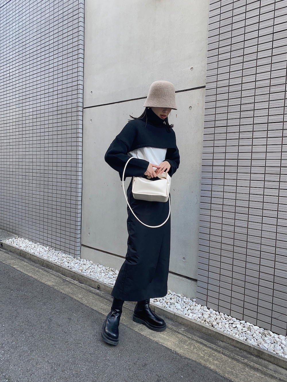 ブラック系のニット/セーター、ブラック系のスカート、ホワイト系のTシャツ/カットソーを着用したレディースの冬コーディネートの3枚目の写真