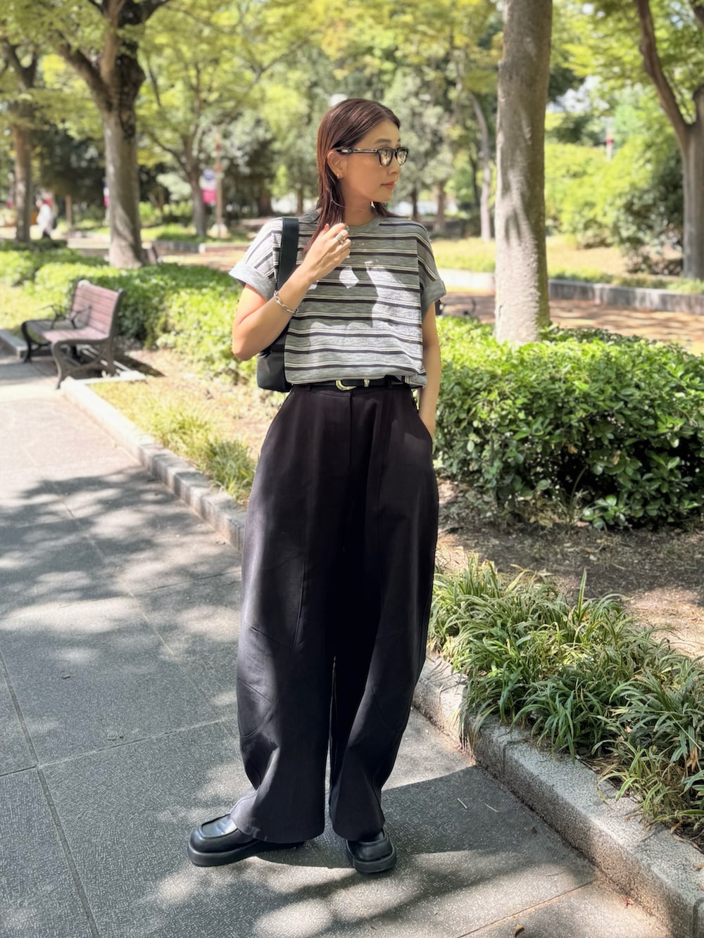 ブラック系のショルダーバッグ、ブラック系のチノパンツ、ブラック系のローファーを着用したレディースの秋コーディネートの2枚目の写真