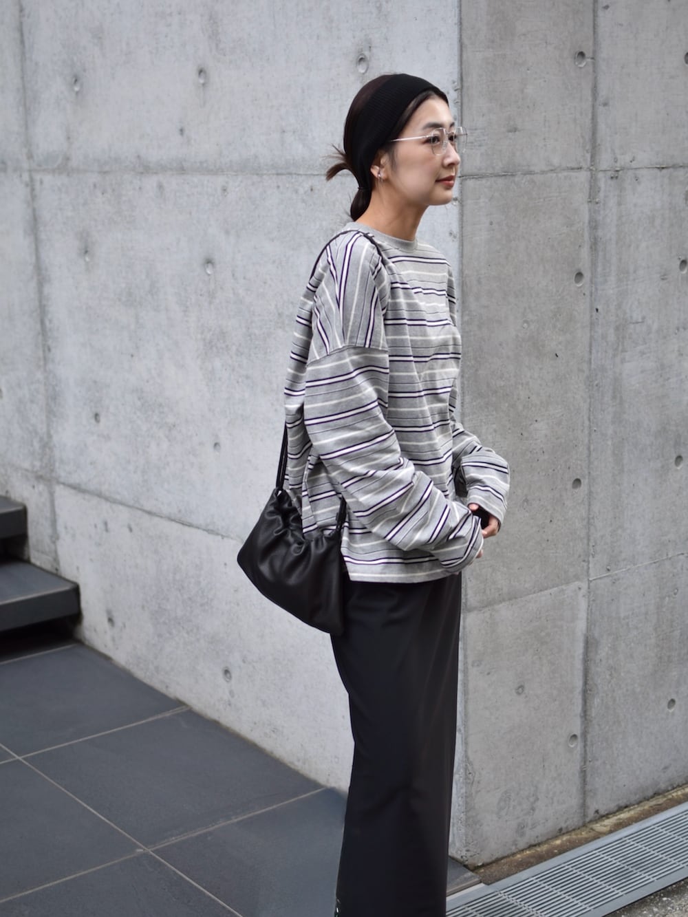 グレー系のTシャツ/カットソー、ブラック系のスカート、ブラック系のスニーカーを着用したレディースの春コーディネートの3枚目の写真