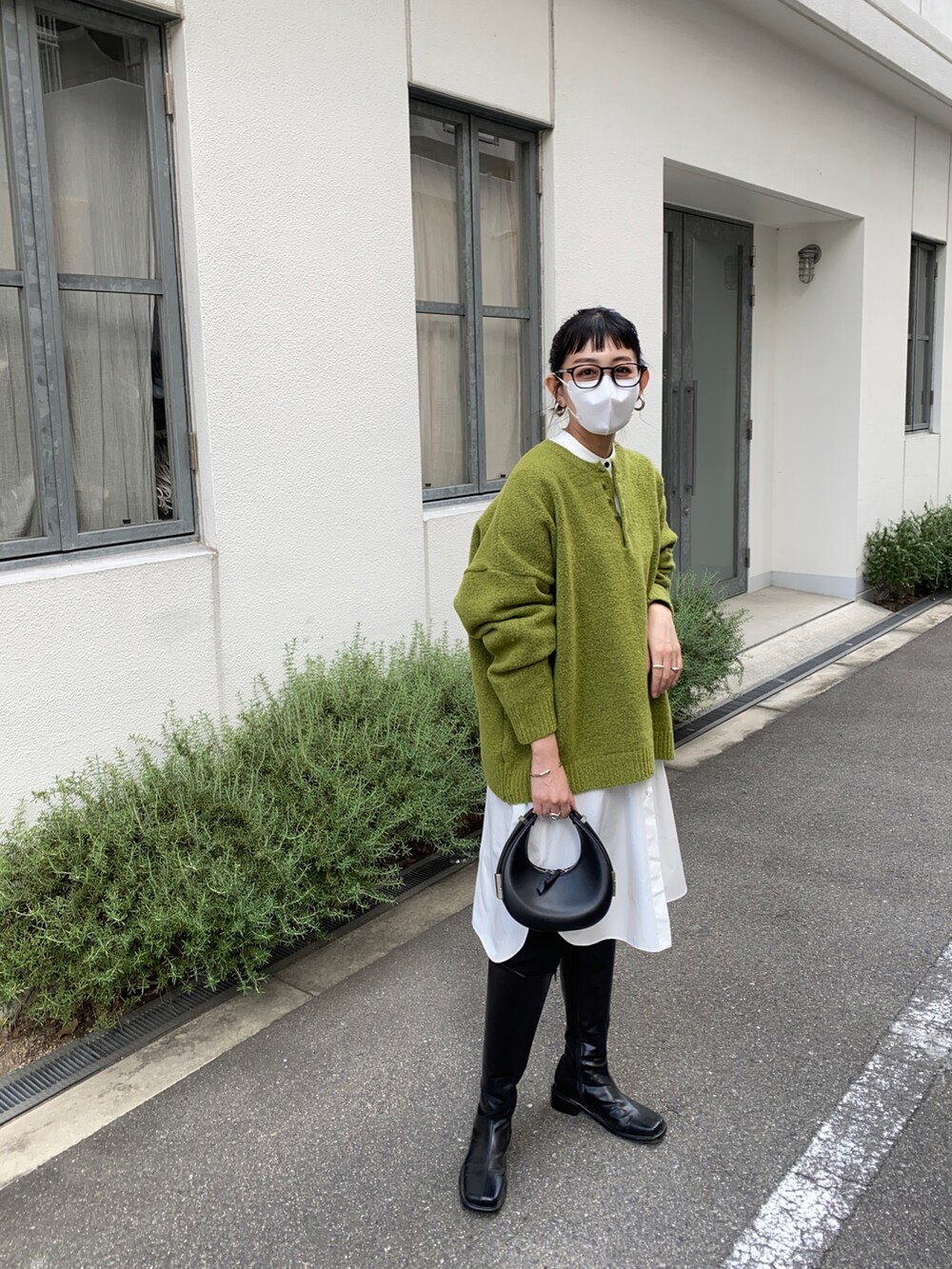 グリーン系のニット/セーター、ホワイト系のシャツワンピースを着用したレディースの秋コーディネートの4枚目の写真