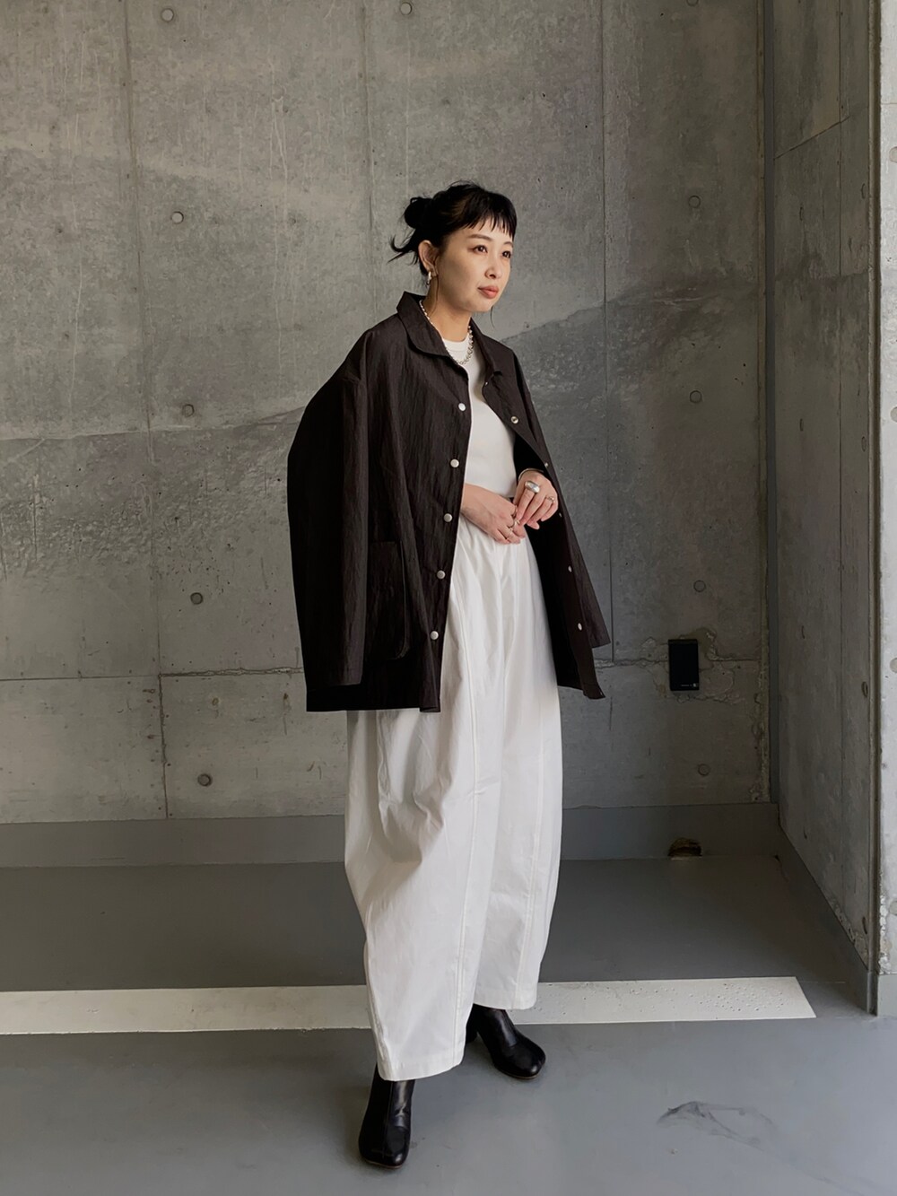 ブラック系のナイロンジャケット、ホワイト系のチノパンツ、ブラック系のブーツを着用したレディースの冬コーディネートの4枚目の写真