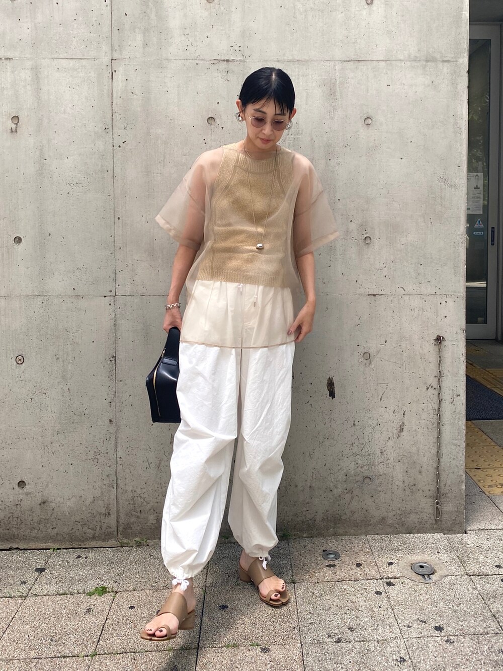 グリーン系のタンクトップ、ベージュ系のシャツ/ブラウス、ブラウン系のサンダルを着用したレディースの夏コーディネートの2枚目の写真