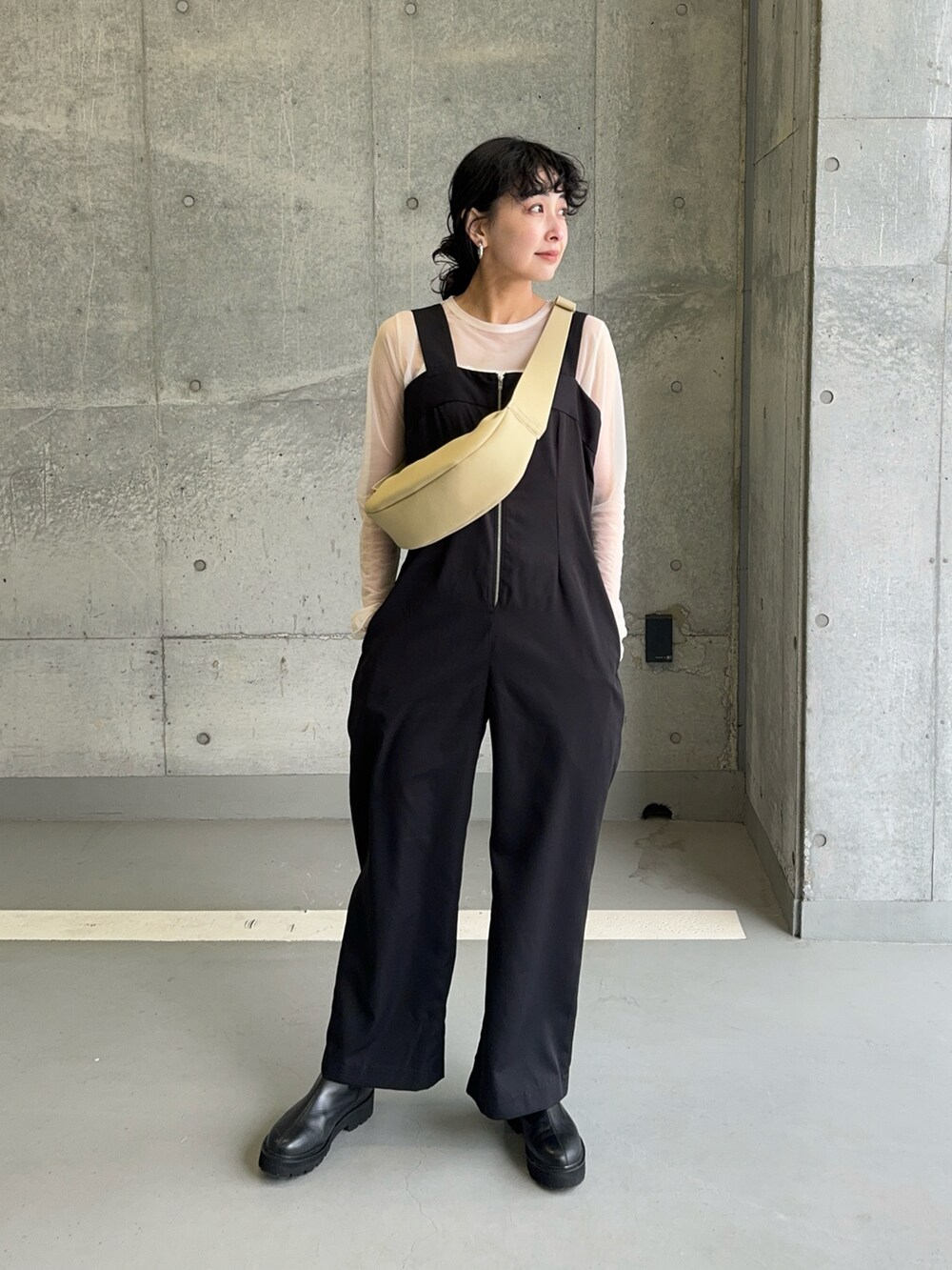 ブラック系のサロペット/オーバーオール、ホワイト系のキャミソール、ベージュ系のショルダーバッグを着用したレディースの春コーディネートの4枚目の写真