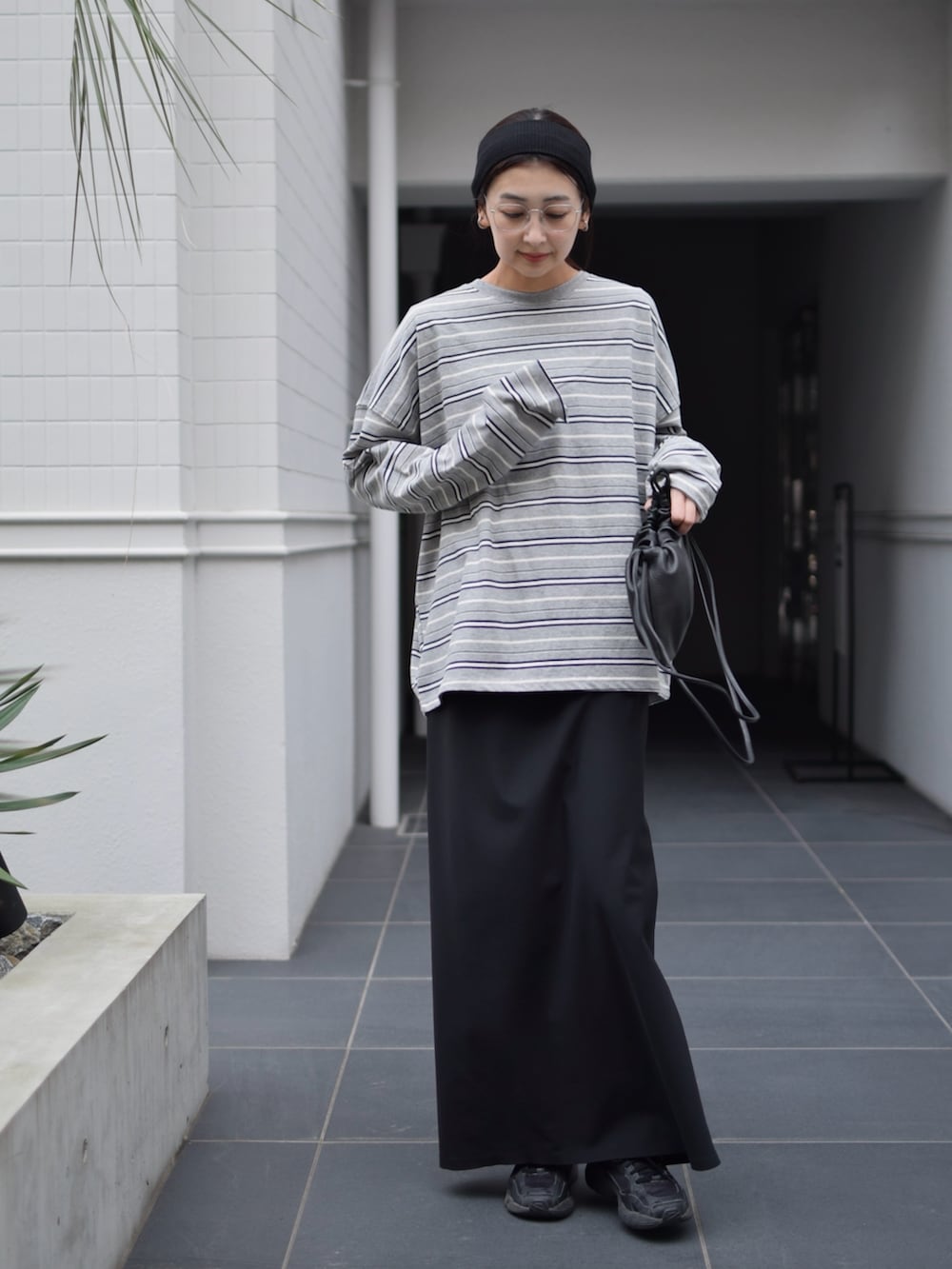 グレー系のTシャツ/カットソー、ブラック系のスカート、ブラック系のスニーカーを着用したレディースの春コーディネートの4枚目の写真