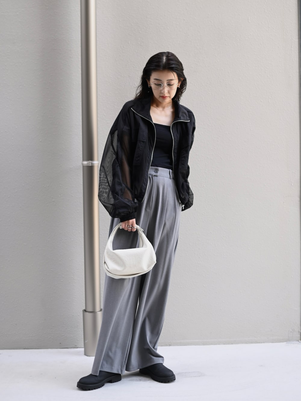 ブラック系のブルゾン、ホワイト系のショルダーバッグ、ブラック系のスリッポンを着用したレディースの秋コーディネートの2枚目の写真