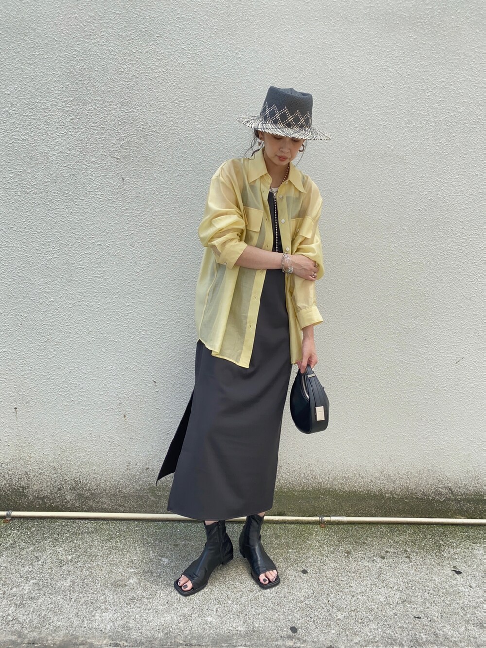 イエロー系のシャツ/ブラウス、ブラック系のワンピース、ブラック系のハンドバッグを着用したレディースの夏コーディネートの2枚目の写真