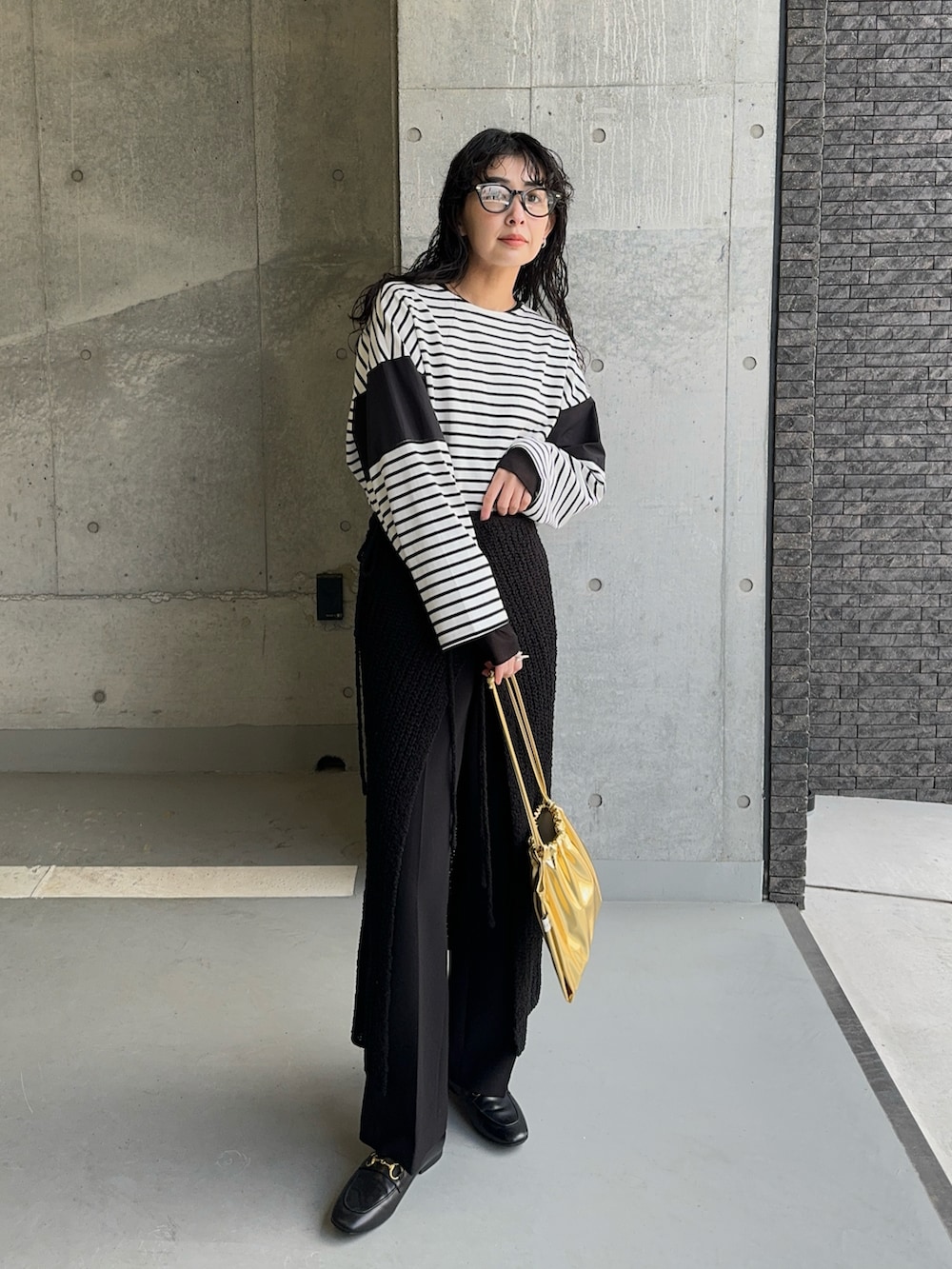 ブラック系のTシャツ/カットソー、ブラック系のスカート、ゴールド系のショルダーバッグを着用したレディースの春コーディネートの2枚目の写真