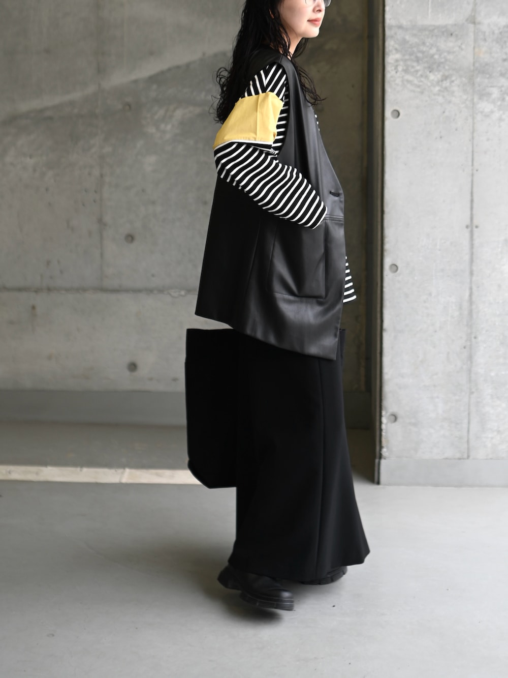 イエロー系のTシャツ/カットソー、ブラック系のスカート、ブラック系のブーツを着用したレディースの春コーディネートの3枚目の写真