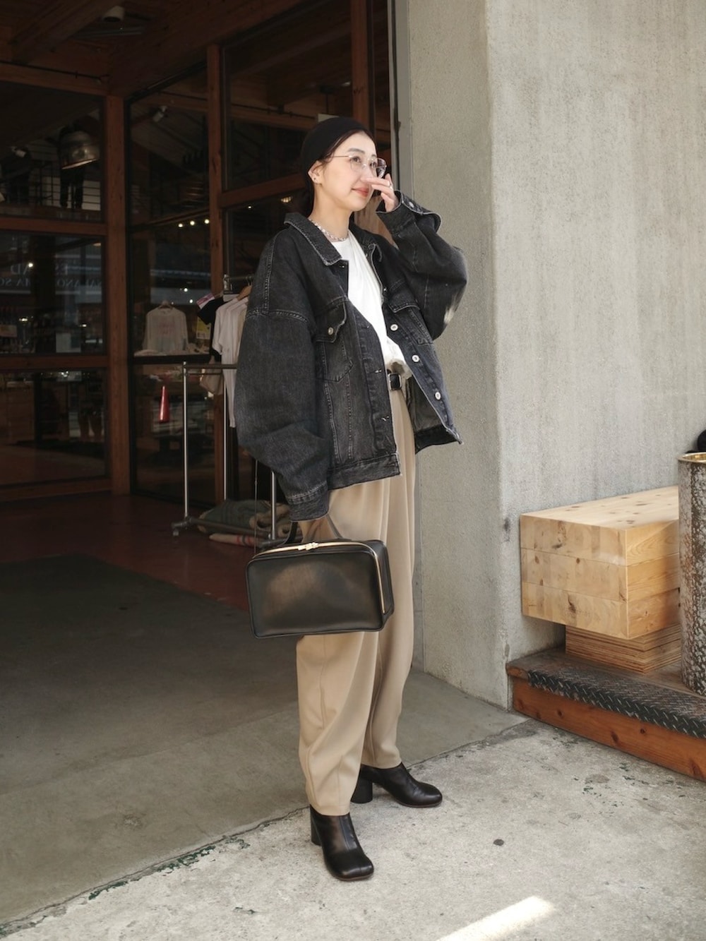 ブラック系のデニムジャケット、ブラック系のハンドバッグ、ブラック系のブーツを着用したレディースの冬コーディネートの2枚目の写真