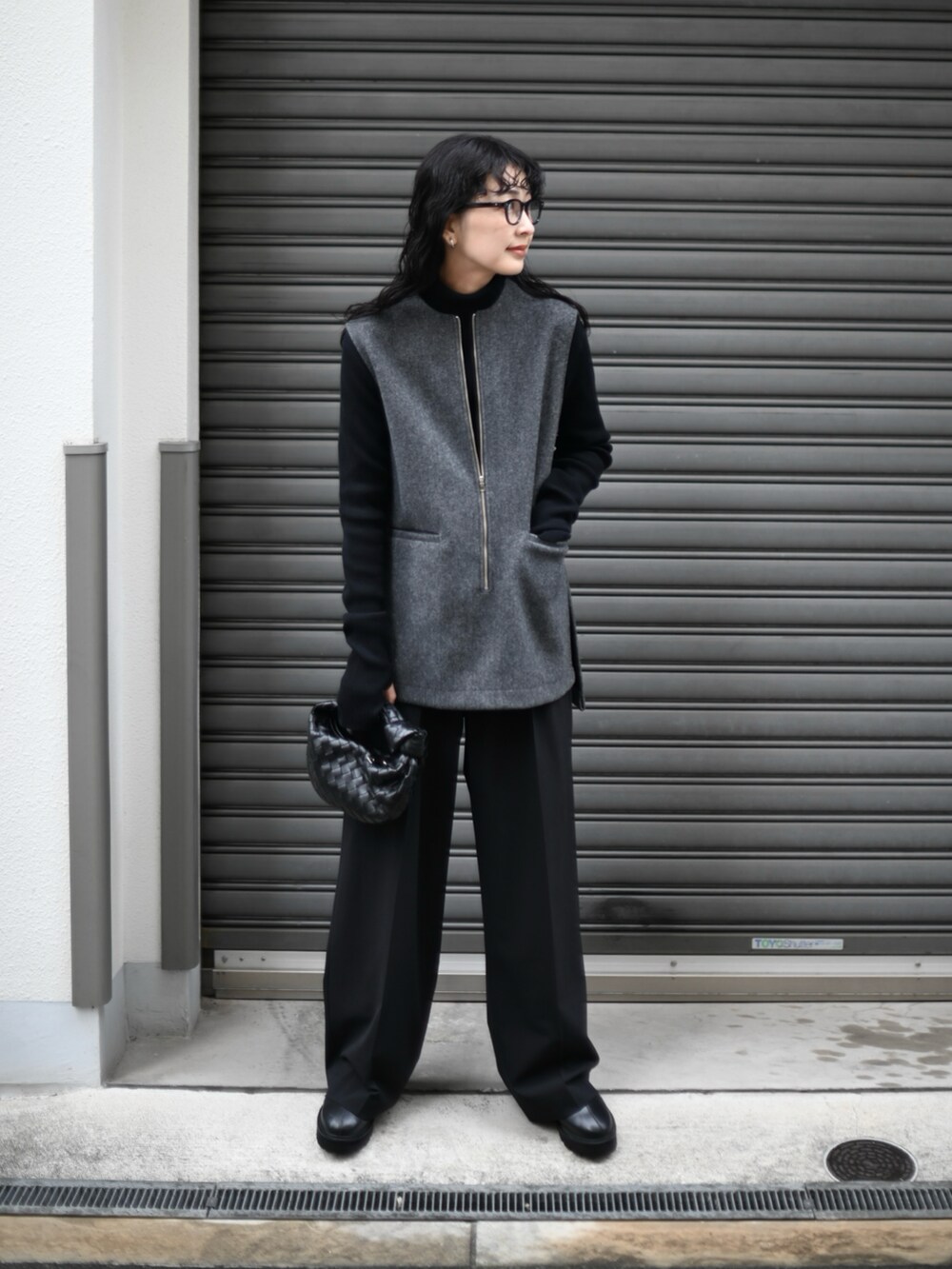 グレー系のベスト、ブラック系のスラックス、ブラック系のブーツを着用したレディースの冬コーディネートの2枚目の写真