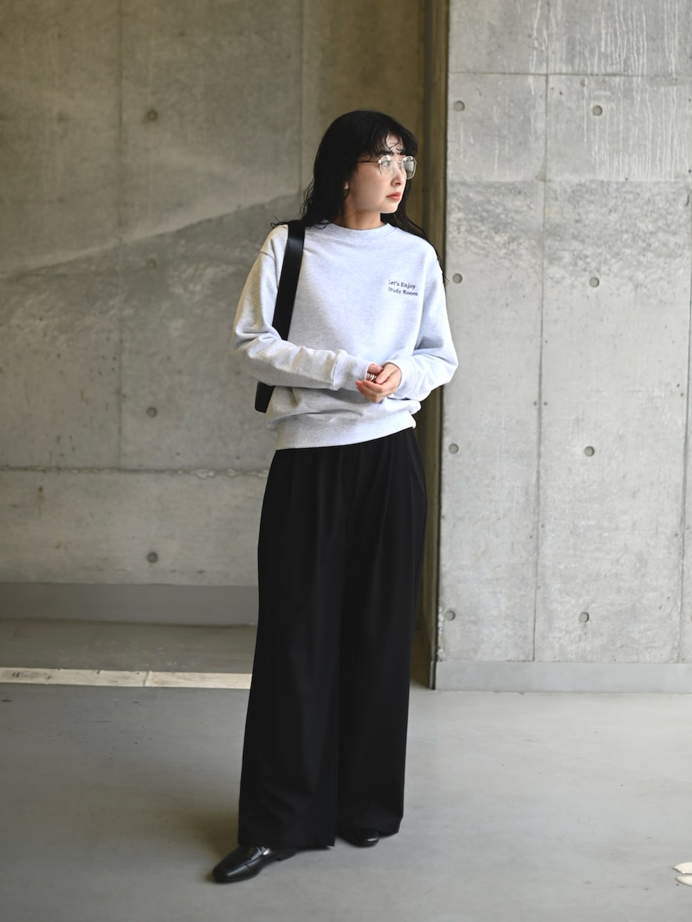 ホワイト系のスウェット、ブラック系のショルダーバッグ、ブラック系のスラックスを着用したレディースの春コーディネートの2枚目の写真