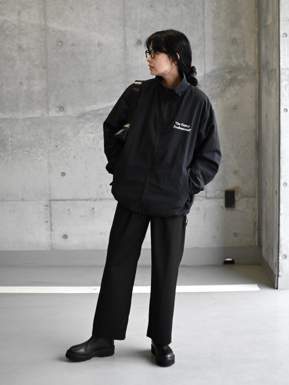 ブラック系のナイロンジャケット、ブラック系のスラックス、ブラック系のブーツを着用したレディースの冬コーディネートの5枚目の写真