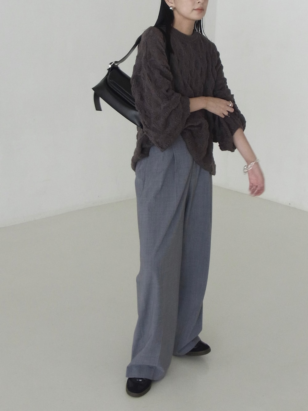 グレー系のニット/セーター、ブラック系のショルダーバッグ、グレー系のスラックスを着用したレディースの秋コーディネートの2枚目の写真