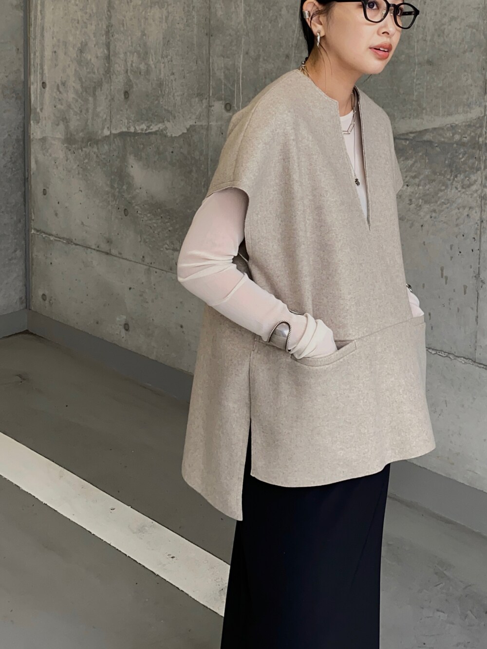 ベージュ系のベスト、ブラック系のスカート、ブラック系のブーツを着用したレディースの秋コーディネートの2枚目の写真