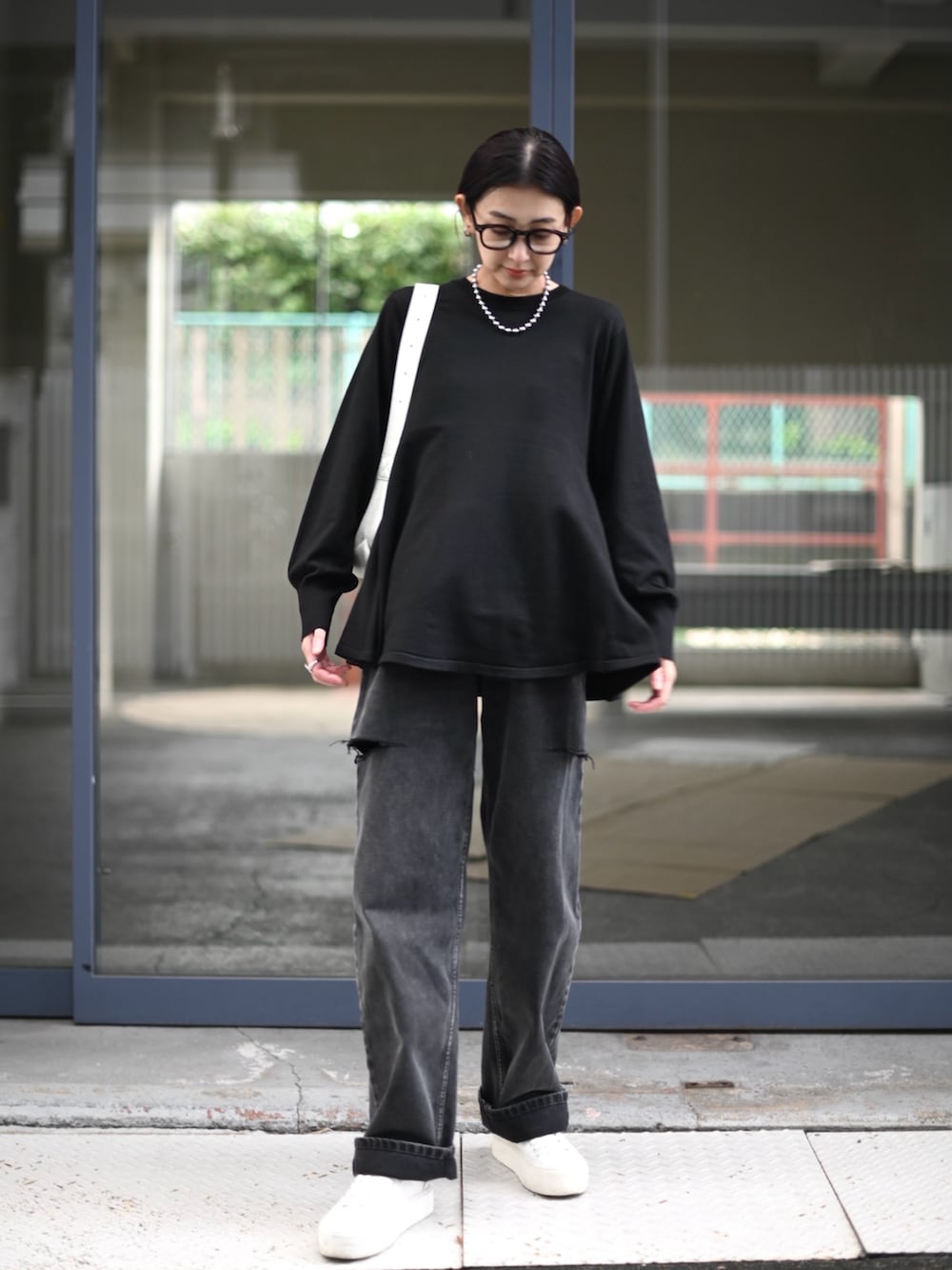 ブラック系のニット/セーター、ブラック系のデニムパンツ、ホワイト系のショルダーバッグを着用したレディースの秋コーディネートの2枚目の写真