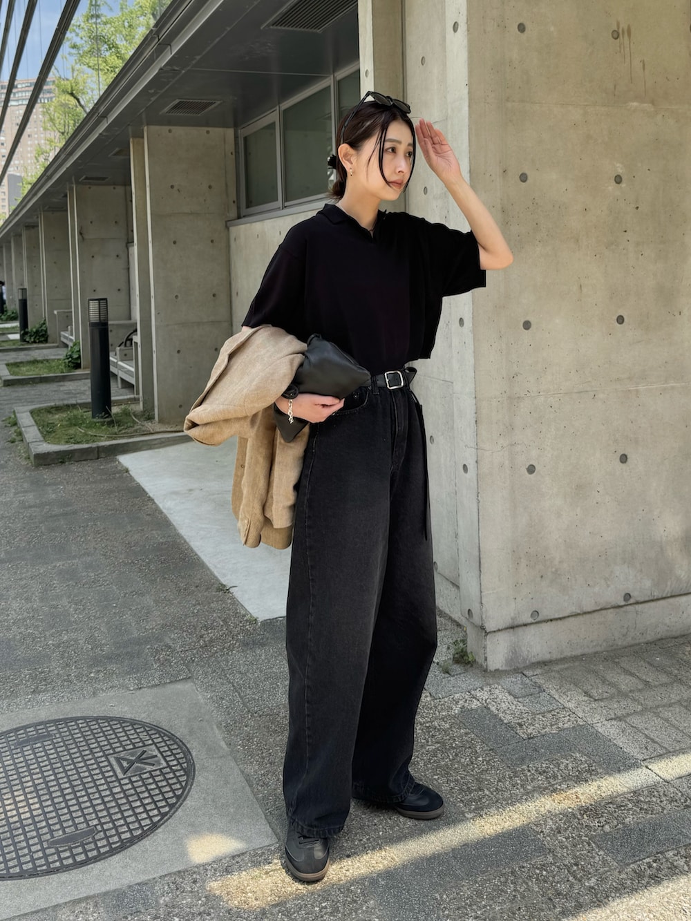 ブラック系のポロシャツ、ブラック系のデニムパンツ、ブラック系のスニーカーを着用したレディースの春コーディネートの5枚目の写真