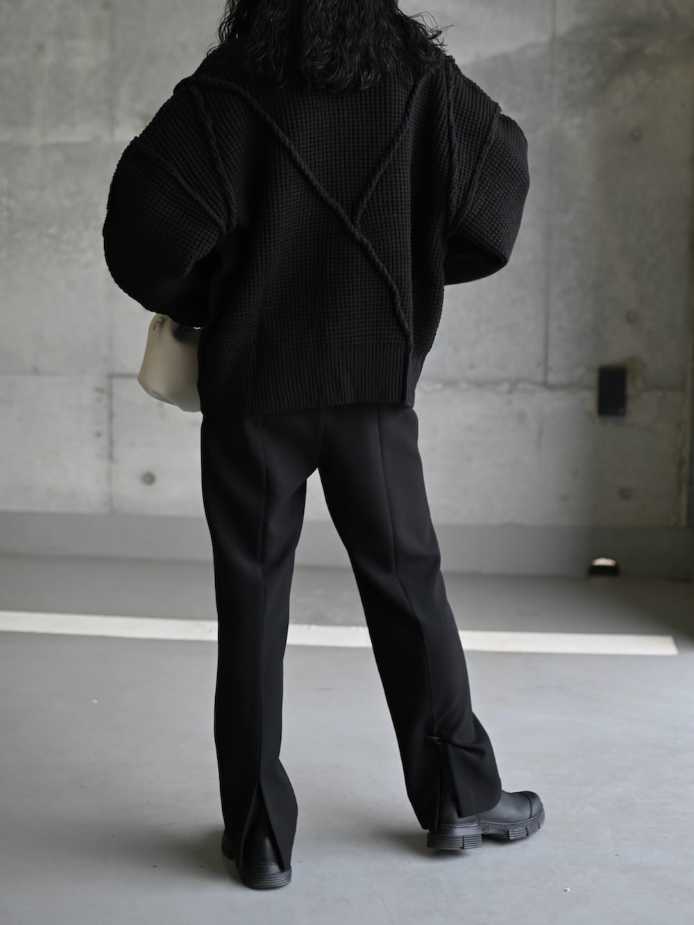 ブラック系のニット/セーター、グレー系のTシャツ/カットソー、ブラック系のブーツを着用したレディースの秋コーディネートの4枚目の写真