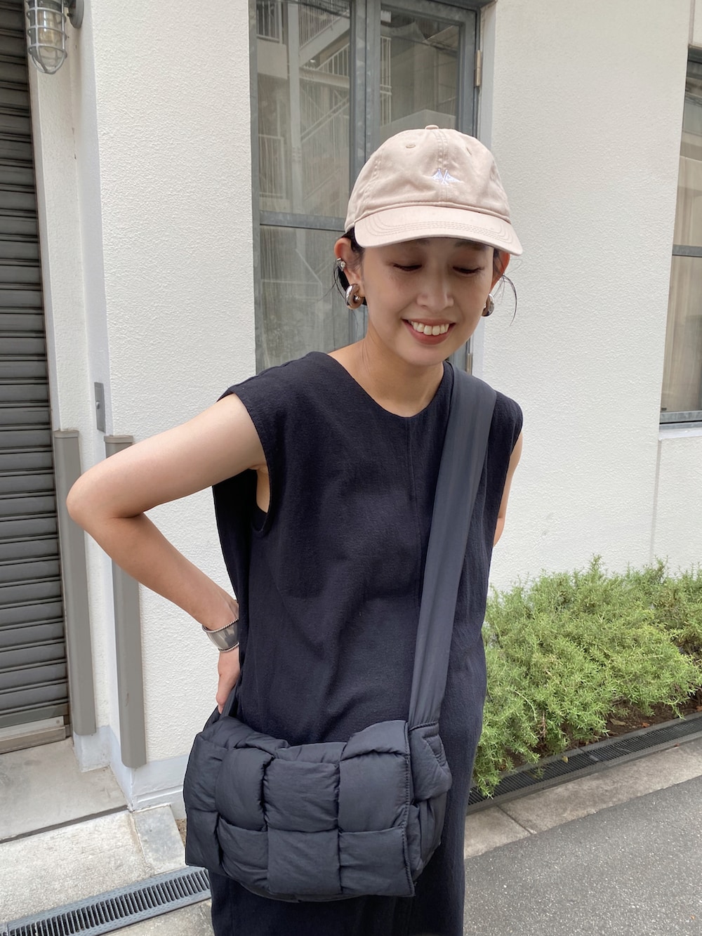 ブラック系のワンピース、ブラック系のショルダーバッグ、ホワイト系のスニーカーを着用したレディースの夏コーディネートの2枚目の写真