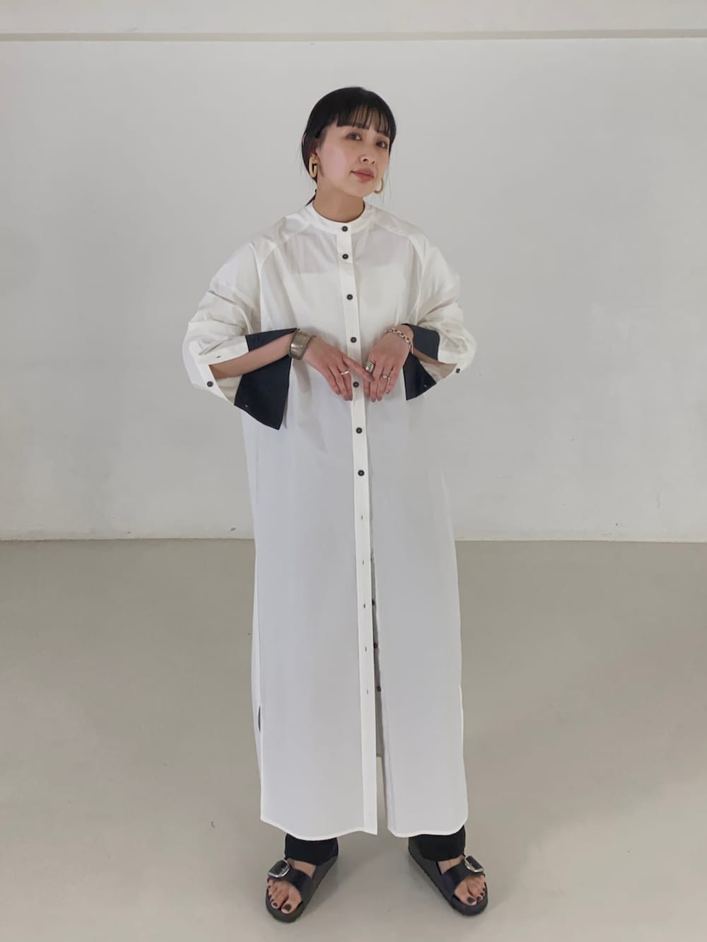 ホワイト系のシャツワンピース、ブラック系のサンダルを着用したレディースの夏コーディネートの4枚目の写真