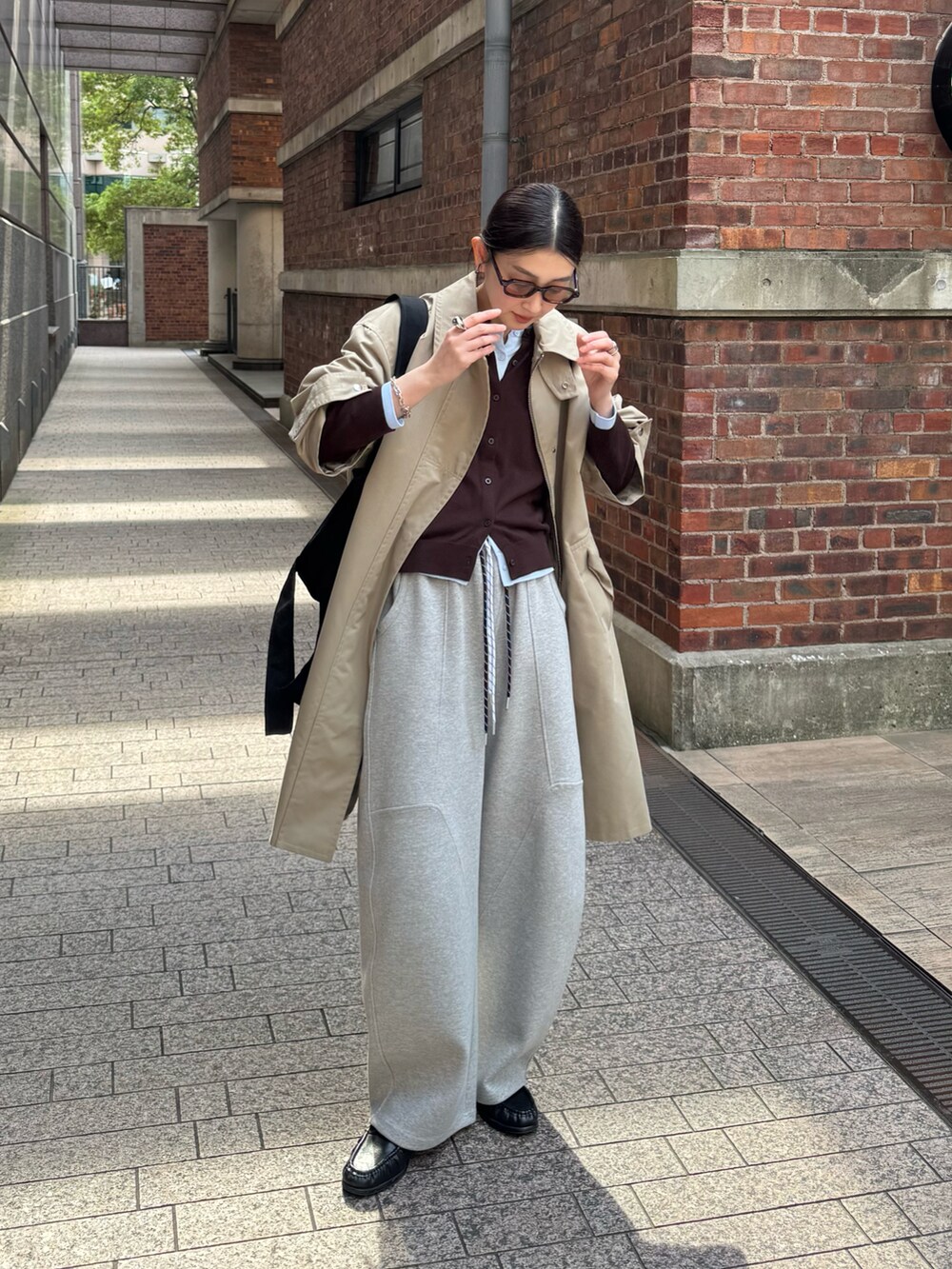 ブラック系のトートバッグ、ベージュ系のステンカラーコート、ブルー系のカーディガン/ボレロを着用したレディースの春コーディネートの2枚目の写真