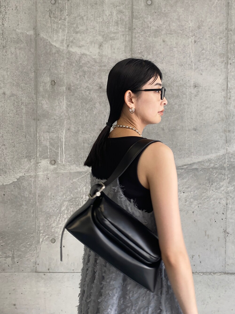 グレー系のワンピース、ブラック系のショルダーバッグ、ブラック系のメガネを着用したレディースの夏コーディネートの2枚目の写真