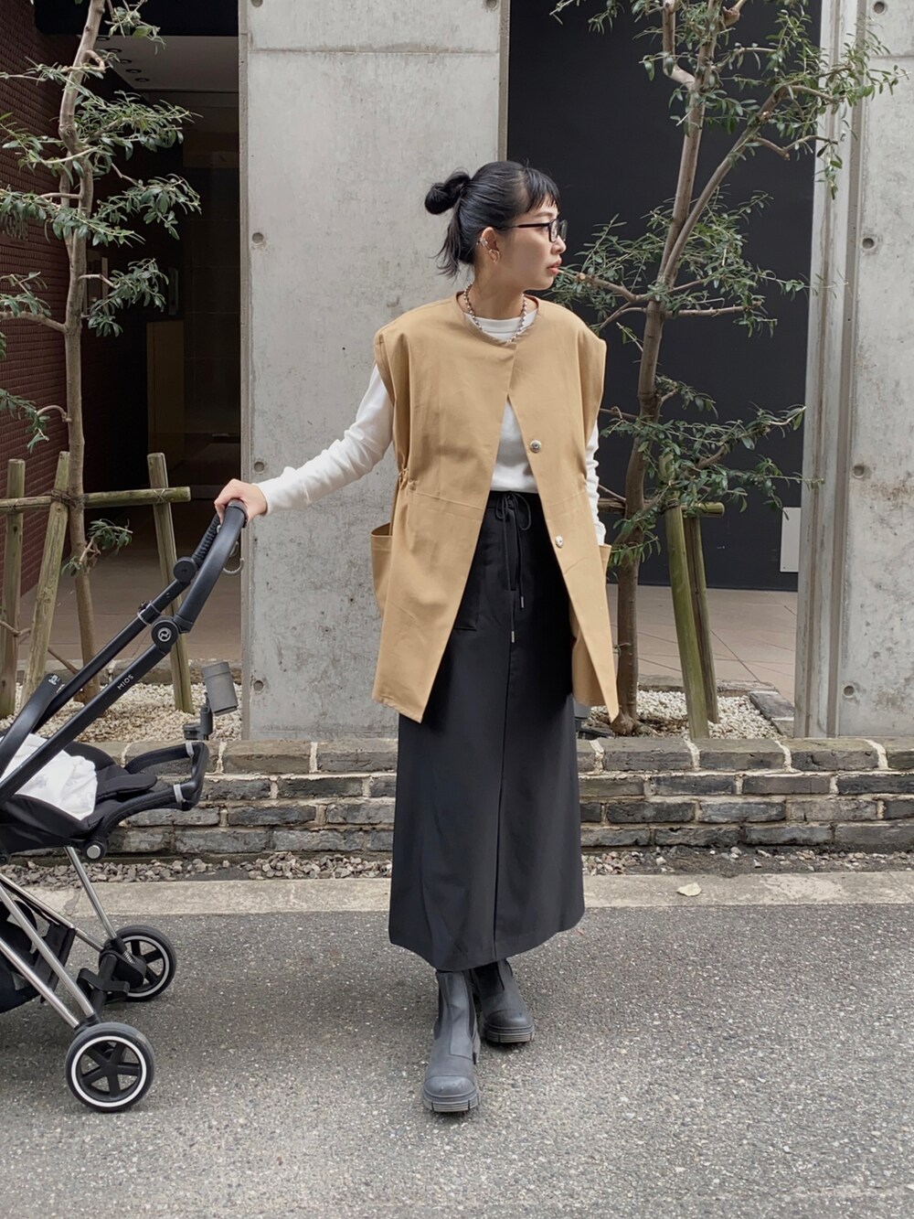 ベージュ系のベスト、ホワイト系のTシャツ/カットソー、ブラック系のスカートを着用したレディースの秋コーディネートの3枚目の写真