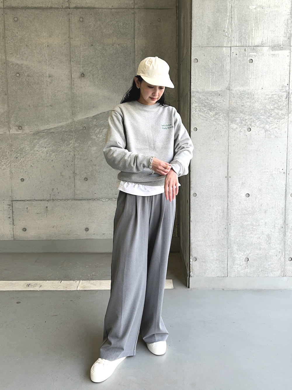 グレー系のスウェット、グレー系のスラックス、ホワイト系のスニーカーを着用したレディースの春コーディネートの4枚目の写真