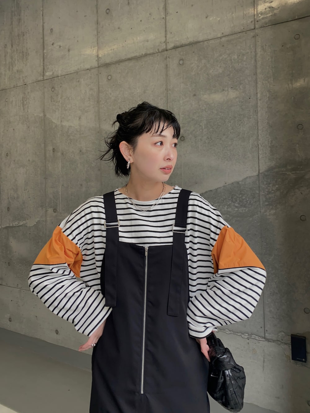 ブラック系のブーツ、オレンジ系のTシャツ/カットソー、ブラック系のジャンパースカートを着用したレディースの春コーディネートの3枚目の写真