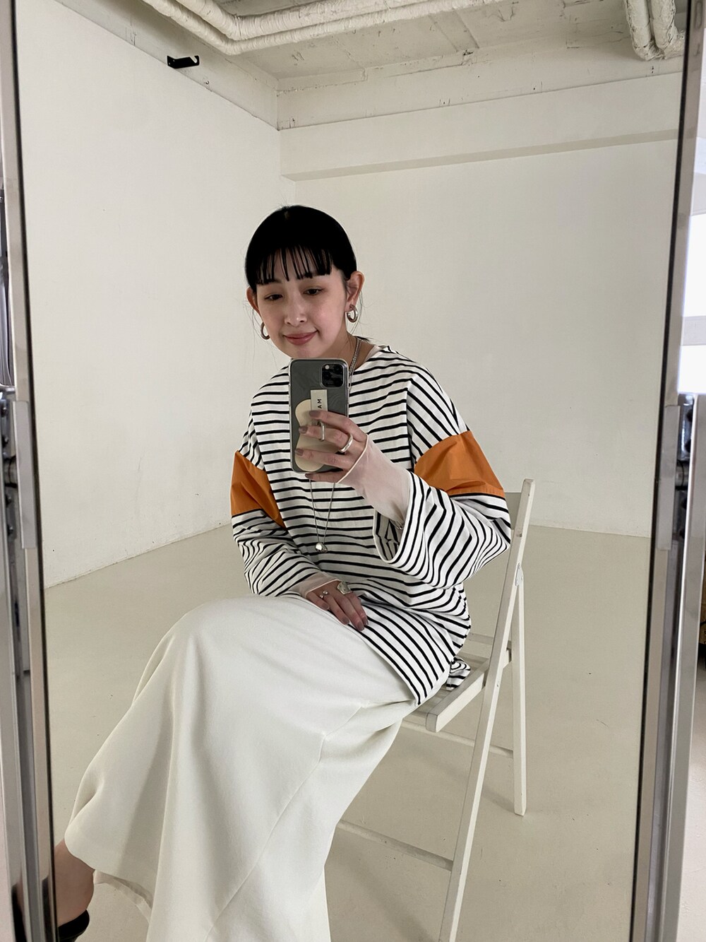 オレンジ系のTシャツ/カットソー、ホワイト系のキャミソール、シルバー系のネックレスを着用したレディースの春コーディネートの2枚目の写真