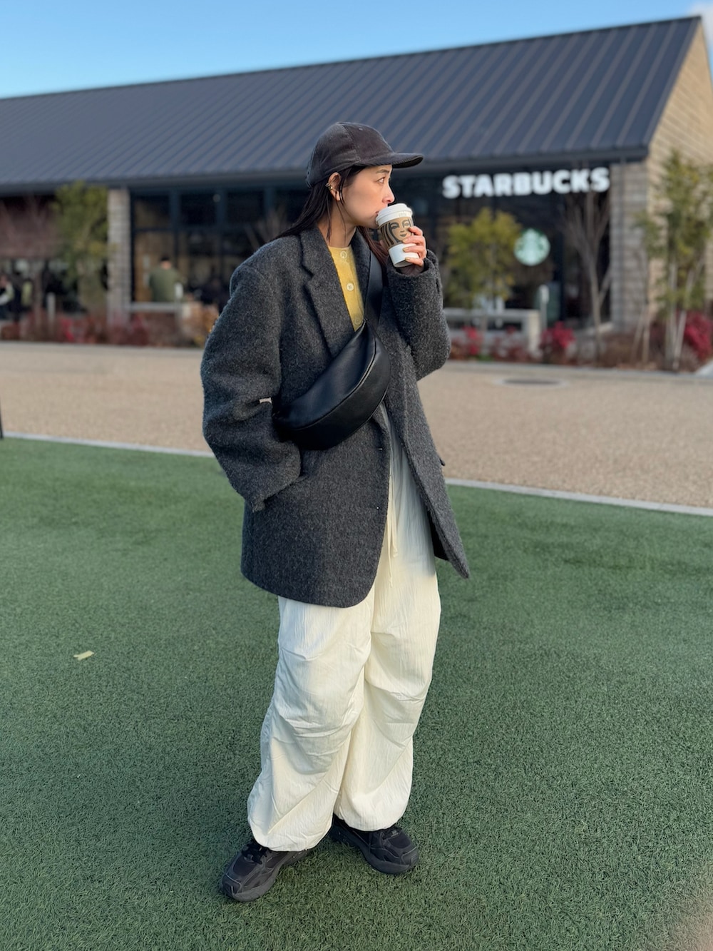 ブラック系のショルダーバッグ、イエロー系のカーディガン/ボレロ、ホワイト系のその他パンツを着用したレディースの冬コーディネートの2枚目の写真