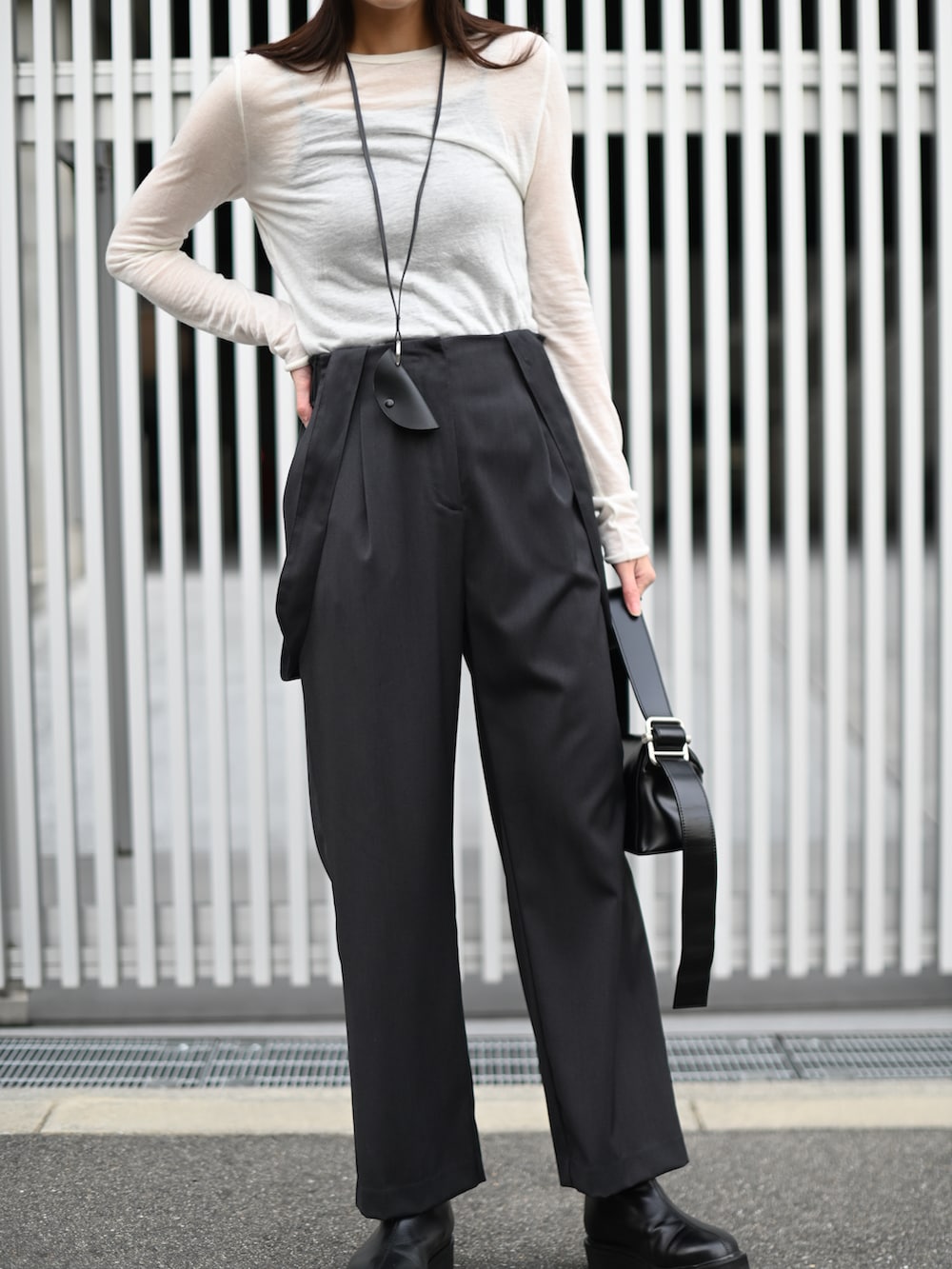 グレー系のスラックス、ブラック系のブーツ、ブラック系のショルダーバッグを着用したレディースの冬コーディネートの4枚目の写真