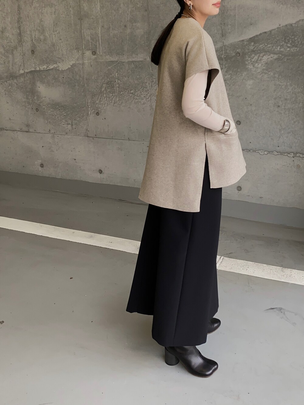 ベージュ系のベスト、ブラック系のスカート、ブラック系のブーツを着用したレディースの秋コーディネートの3枚目の写真