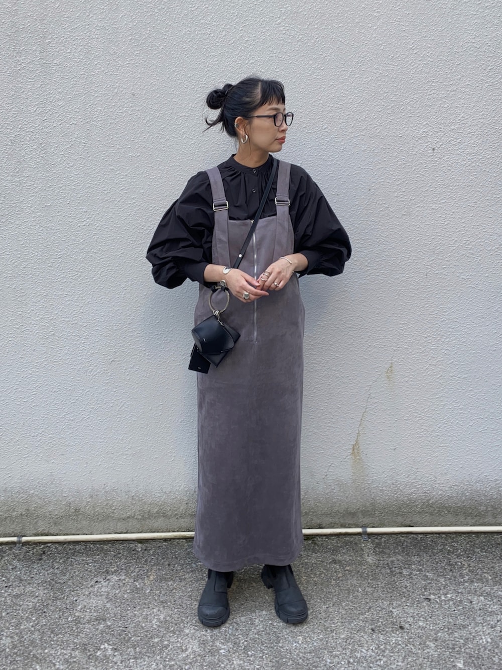 グレー系のジャンパースカート、ブラック系のシャツ/ブラウス、ブラック系のブーツを着用したレディースの冬コーディネートの4枚目の写真