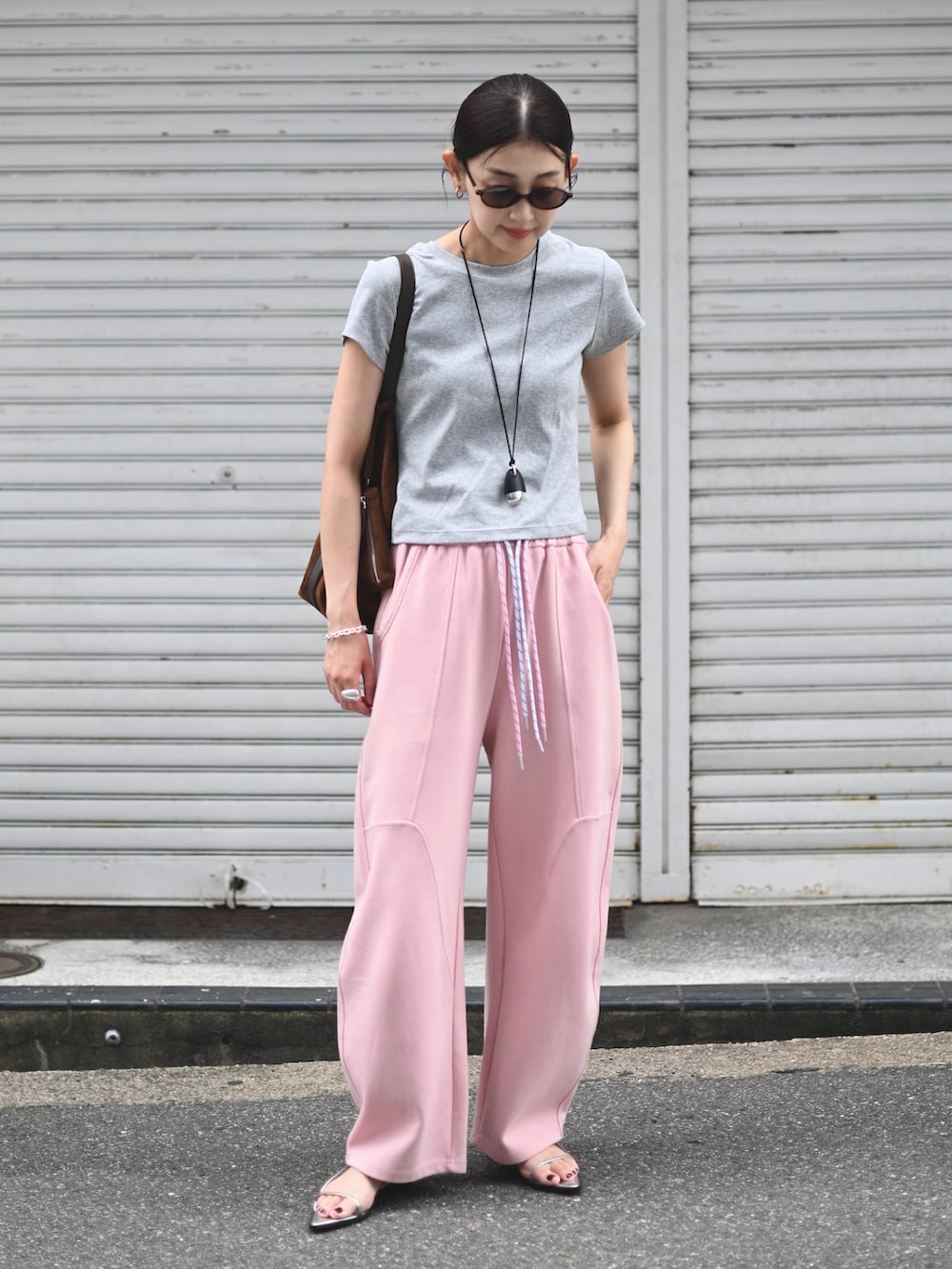 ピンク系のスウェットパンツ、グレー系のTシャツ/カットソー、ブラウン系のトートバッグを着用したレディースの夏コーディネートの5枚目の写真
